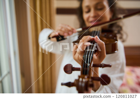 Close-up of woman playing a violin with focus on fingers and bow Close-up of woman playing a violin with focus on fingers and bow 120811027