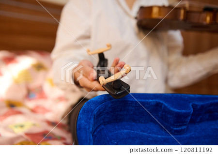 Musician adjusting violin shoulder rest in cozy home environment 120811192