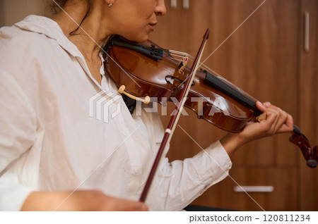 Woman gracefully playing violin in a cozy indoor setting 120811234
