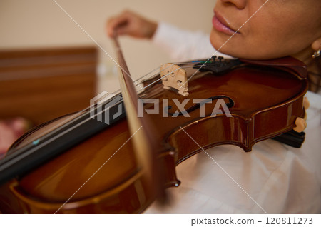 Close-up of a woman playing a violin with focused expression 120811273