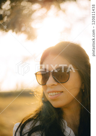 A woman wearing sunglasses. She is smiling and she is enjoying her walk. 120811438