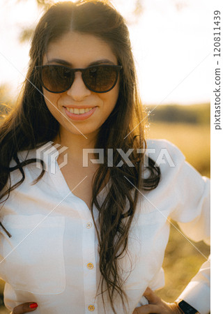 A woman wearing sunglasses. She is smiling and she is enjoying her walk. 120811439