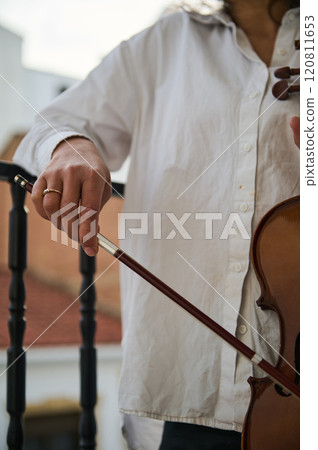 Musician playing violin outdoors with focused hands on strings and bow Musician playing violin outdoors with focused hands on strings and bow 120811653