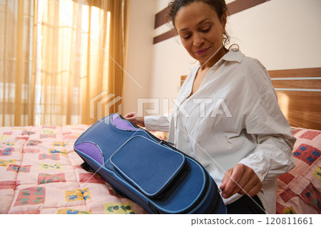 Woman preparing suitcase on bed for a vacation trip 120811661