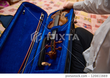 Person carefully holding a violin in a blue velvet lined case Person carefully holding a violin in a blue velvet lined case 120811669