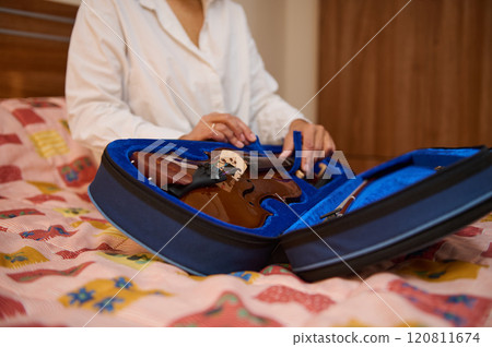 Person opening violin case on a bed with colorful patchwork quilt Person opening violin case on a bed with colorful patchwork quilt 120811674
