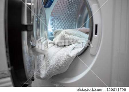Opened dryer machine full of white clothes. Closeup. Front view. Opened dryer machine full of white clothes. Closeup. Front view. 120811706