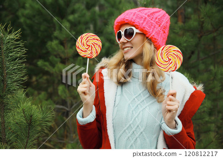 Winter portrait of happy funny smiling young woman having fun against Christmas tree in forest 120812217