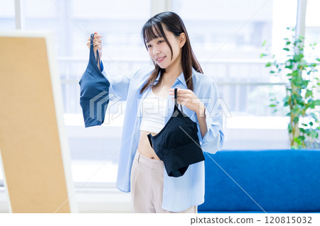 年輕女性在全身鏡前選擇衣服和內衣,選擇運動胸罩和內衣 年輕女性在全身鏡前選擇衣服和內衣,選擇運動胸罩和內衣 120815032