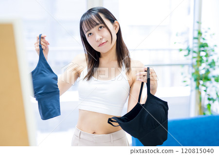 年輕女性在全身鏡前選擇衣服和內衣，選擇運動胸罩和內衣 120815040