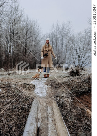 Happy young woman walking with her welsh corgi pembroke puppy, winter nature 120816047