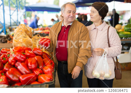 Mature married couple in casual clothes choosing organic bell peppers during date at local grocery market Mature married couple in casual clothes choosing organic bell peppers during date at local grocery market 120816471