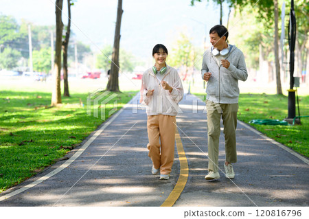 Happy middle aged father and daughter jogging through a beautiful park. Health and family activity concept 120816796