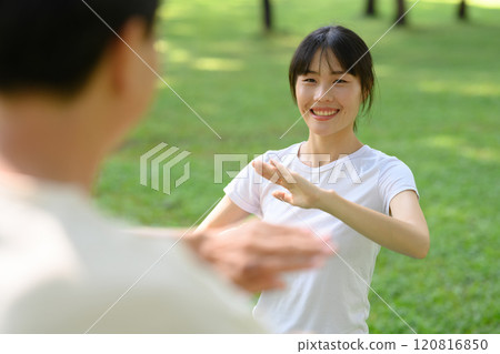 Cheerful asian woman and father practicing Tai Chi in the park. Healthy and outdoor activity concept 120816850