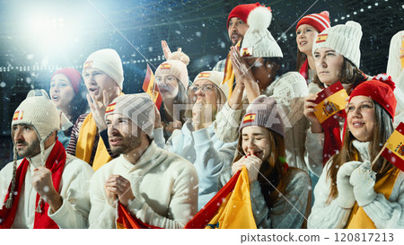 Passionate sports fans, move men and women, dressed in colorful scarves and hats, supporting favorite Spanish team in crowded stadium. Passionate sports fans, move men and women, dressed in colorful scarves and hats, supporting favorite Spanish team in crowded stadium. 120817213