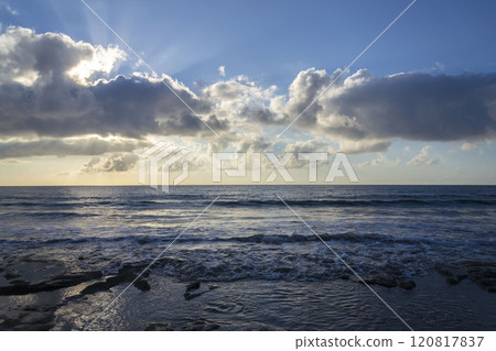 Breathtaking sunrise with sun hiding behind cloud, sea waves and blue sky with copy space Breathtaking sunrise with sun hiding behind cloud, sea waves and blue sky with copy space 120817837