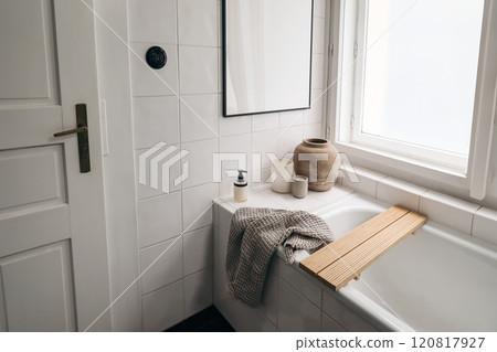 Elegant bathroom. Modern Scandinavian bathroom interior with bathtub. Black picture frame mockup. White tiles wall. Candle, towel, soap dispenser and old vase near window. Top view. 120817927