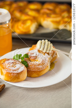 Pastries. Sweet buns with cottage cheese filling and honey in a plate on a wooden table 120818177