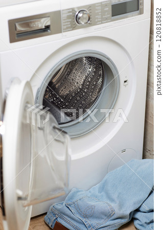 dirty jeans near open washing machine in laundry room. 120818852