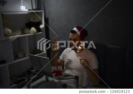 30-year-old man celebrates Christmas, New Year online with colleagues, friends at night with the light of a lamp 30-year-old man celebrates Christmas, New Year online with colleagues, friends at night with the light of a lamp 120819123