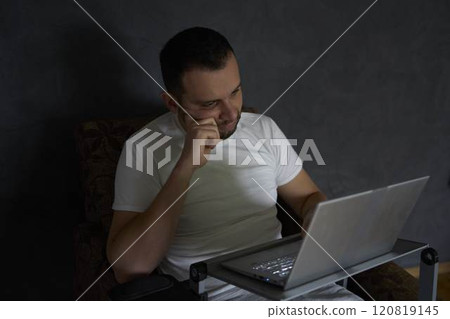 A 30-year-old man is stressed while working on a laptop from his home office 120819145