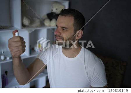 A 30-year-old man applies spray tonic to his skin 120819149