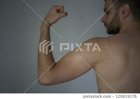 30-year-old man of medium build is straining the muscles on his arm 120819176