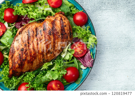 Grilled chicken breast ( fillet ) with lattuce salad and cherry tomatoes . Top view Grilled chicken breast ( fillet ) with lattuce salad and cherry tomatoes . Top view 120819477