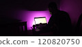Young man silhouette sitting computer laptop in studio on violet background 120820750