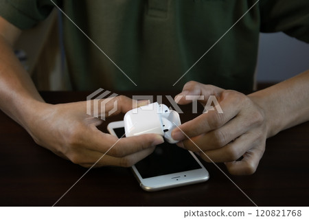 An Asian man is about to use wireless headphones that connect to his smartphone. An Asian man is about to use wireless headphones that connect to his smartphone. 120821768