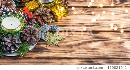 Christmas brown wooden background with a composition of candles with cones, lights, golden gifts and snowflakes. New Year's home wall decor different angles handmade top view 120821941