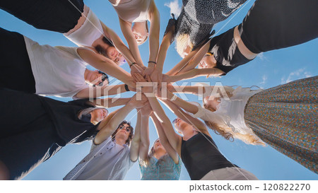 Group of young women is joining hands in a circle outdoors, showing their unity and teamwork Group of young women is joining hands in a circle outdoors, showing their unity and teamwork 120822270