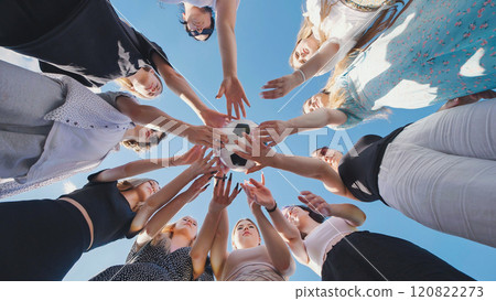 Friends join hands over a soccer ball and then toss it above them. Friends join hands over a soccer ball and then toss it above them. 120822273