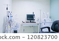 A respiratory therapy room equipped with a pulmonary function test machine, nebulizers, and oxygen therapy equipment. The room features a patient examination chair 120823700