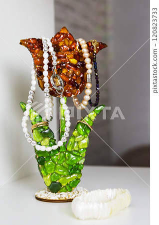 A flowershaped holder organizes necklaces and rings on a table A flowershaped holder organizes necklaces and rings on a table 120823733