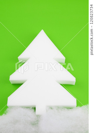 A white styrofoam Christmas tree stands out on a beautiful green background 120823734