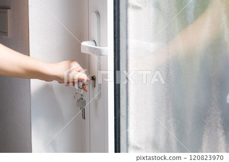 Hand on a door handle while turning a key to unlock a modern white door. Hand on a door handle while turning a key to unlock a modern white door. 120823970