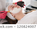 Aesthetician carefully applies an even layer of clay mask to the client's face, providing deep cleansing and balancing for the skin 120824007