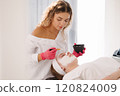 Skincare specialist distributes the clay mask thoroughly over the client's face, ensuring even coverage for a balanced complexion 120824009