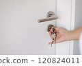 Side view of hand inserting keys into a door lock with a sleek, modern design. 120824011