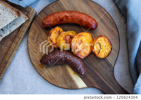Close-up of homemade sausages on wooden cutting board with potatoes. homemade traditional food Close-up of homemade sausages on wooden cutting board with potatoes. homemade traditional food 120824304