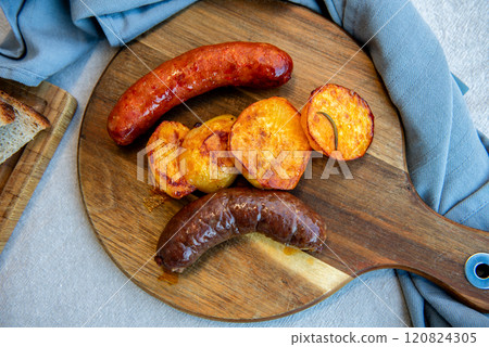 Close-up of homemade sausages on wooden cutting board with potatoes. homemade traditional food Close-up of homemade sausages on wooden cutting board with potatoes. homemade traditional food 120824305