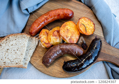 Close-up of homemade blood sausage, pork sausage and chorizo on wooden board with potatoes. homemade traditional food 120824307