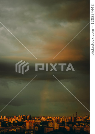 rainbow appeared against gray stormy sky over residential area of the city. 120824448