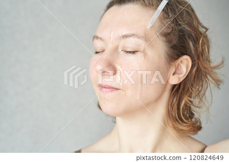 Adult caucasian female applying skincare serum with dropper for facial Adult caucasian female applying skincare serum with dropper for facial 120824649