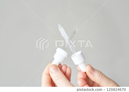 Hands holding dropper caps against neutral background for skincare and cosmetics 120824670
