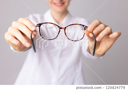 ophthalmologist doctor putting glasses on patient, pulling glasses forward, vision concept ophthalmologist doctor putting glasses on patient, pulling glasses forward, vision concept 120824779