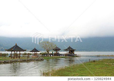 Traditional gazebos on the Bratan mountain lake in cloudy weather on the popular tourist island of Bali. Traditional gazebos on the Bratan mountain lake in cloudy weather on the popular tourist island of Bali. 120824944