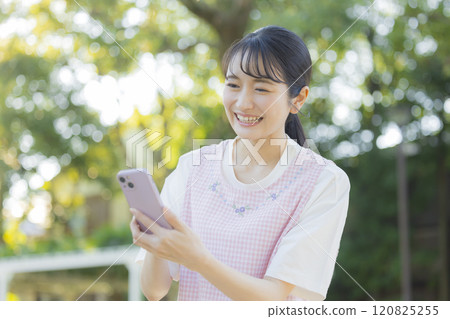 一位有智慧型手機的年輕女托兒所老師 120825255
