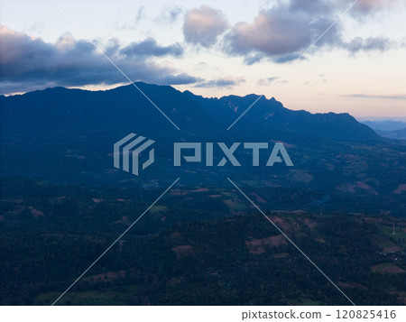 Sunset over mountain range showcasing vast valleys and lush landscapes 120825416